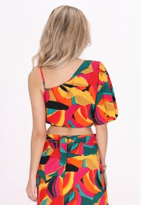 Farbiger Top mit einem Ärmel und puffigem Ärmel, gekennzeichnet durch kräftige Blumenmuster in Rot, Orange, Gelb und Grün; verkürztes Design.