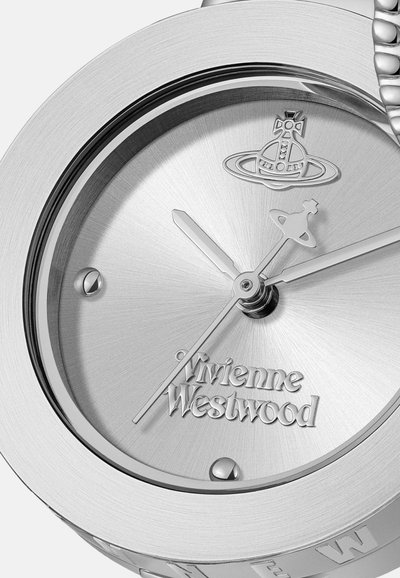 Montre en acier inoxydable argenté avec une texture brossée, dotée d'un cadran minimaliste, d'un logo et de trois aiguilles. Design circulaire avec un bracelet robuste.