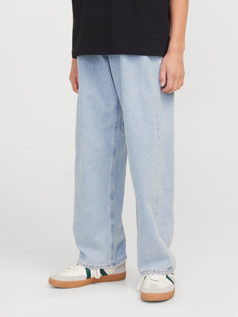 Lyseblå, vide jeans laget av denim med en avslappet passform og standard fem-lommers design, kombinert med beige og grønne joggesko.