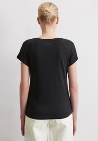 T-shirt noir à manches courtes avec un col rond. Tissu doux et coupe décontractée, arborant un logo discret au niveau du haut du dos.