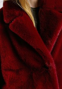 Cappotto in pelliccia sintetica bordeaux con ampio rever, texture morbida e chiusura a un solo bottone. Presenta un pelo folto e profondo per un calore aggiuntivo.