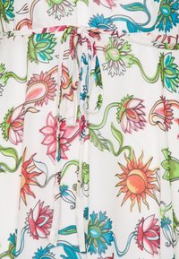 Robe fleurie avec un fond blanc et des motifs de fleurs et de vignes colorés et détaillés. Comprend un lien à la taille.