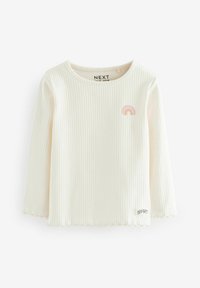 Top blanco de manga larga con textura acanalada y un dobladillo con forma de ondas. Presenta un gráfico de arcoíris pastel en el pecho y un pequeño logo cerca del dobladillo.