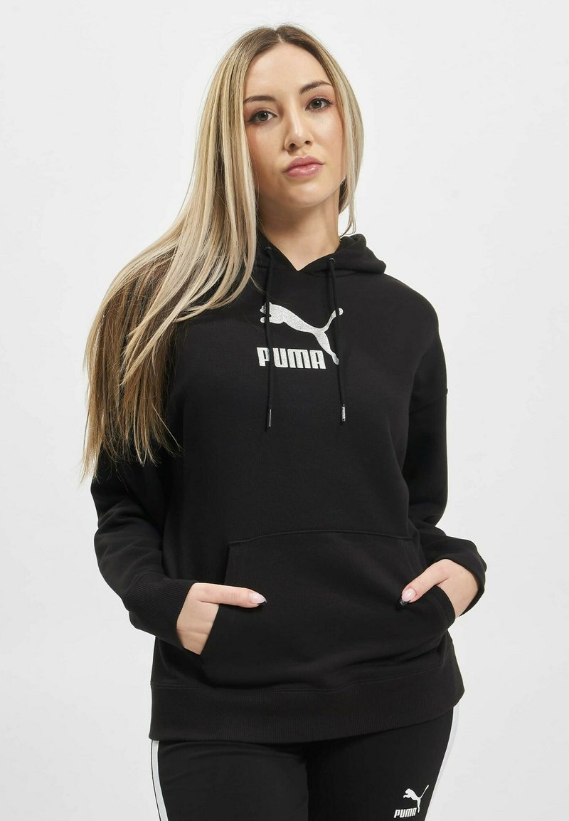 Čierna mikina z jemnej látky s predným vreckom, s bielym logom Puma umiestneným na hrudi a nastaviteľnou kapucňou so šnúrkami.