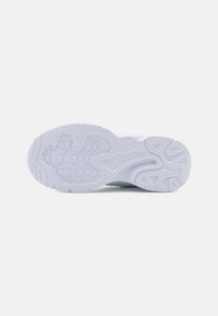 Semelle de chaussure de sport blanche avec une surface en caoutchouc texturé, des rainures en motifs et une zone de talon lisse et renforcée.