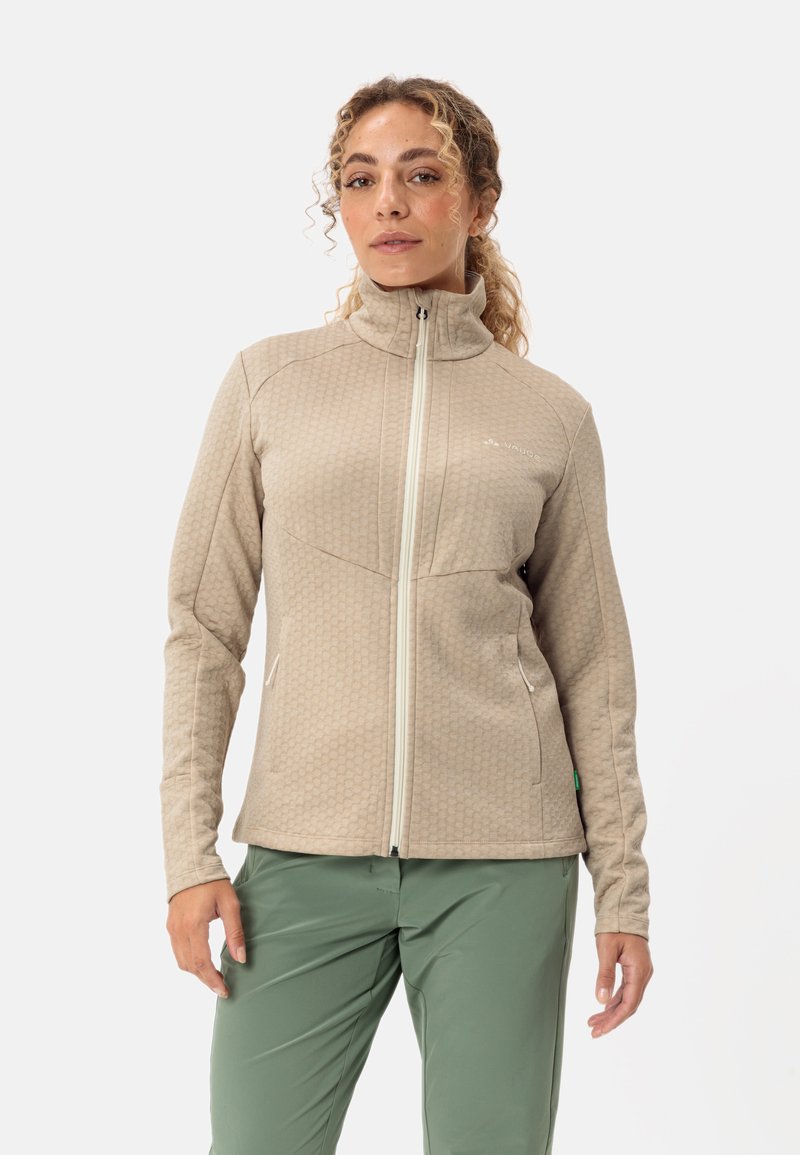 Giacca in fleece beige con un motivo testurizzato a nido d'ape, colletto alto, chiusura frontale con zip e tasche laterali. Dettagli accentati in verde visibili.