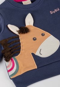 Navyblaues Sweatshirt mit einer braunen Pferdeapplikation, die mit gestickten Details, einer strukturierten Mähne und bunten gestreiften Akzenten an der Seite versehen ist.