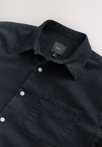 Schwarzes Hemd zum Knöpfen mit Kragen, mit Brusttasche und weißen Knöpfen. Hergestellt aus strukturiertem Stoff und zeigt ein lässiges Design.