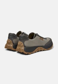 Scarpe outdoor con upper in tela grigia, dettagli scuri e suola in gomma marrone robusta con battistrada testurizzato per una buona aderenza.