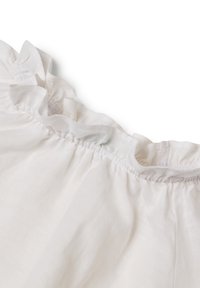 Tessuto di lino bianco con dettaglio di rientro arricciato al collo, che mostra una texture morbida e un aspetto leggero.