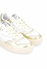 Zapatillas blancas con acentos metálicos dorados, material de cuero suave, diseño de punta perforada, cordones planos y suela de goma gruesa.