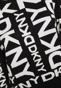 Tissu noir et blanc avec des motifs textuels audacieux et superposés comportant le nom de la marque "DKNY" en grandes lettres.
