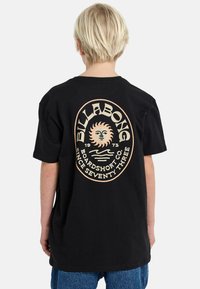 Zwarte katoenen t-shirt met een grote vintage-stijl grafiek op de achterkant, met een zonillustratie en retro tekst in crèmekleurig en oranje.