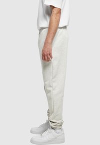 Ljust grå sweatpants med elastisk midja, med något avsmalnande ben. Matchat med vita sneakers för en avslappnad look.
