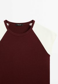 Bordeaux t-shirt med korte creme raglanærmer. Blødt stof, rund halsudskæring og sidesyning detaljer. Mærketikette synlig ved halsen.