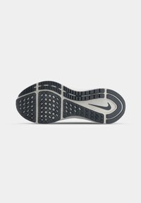 Nike-Schuhsohle von unten betrachtet, mit einer strukturierten schwarzen Gummifläche und einer grauen Mittelsohle, einer rautenförmigen Profilierung und dem Nike-Logo.
