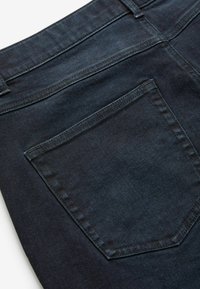 Jeans din denim închis cu un ușor luciu, având un buzunar pe spate cu cusături contrastante și o textură netedă.