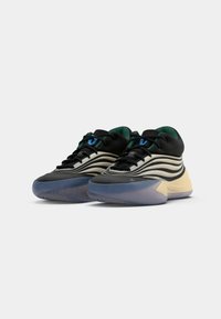 Un paio di scarpe sportive basse con design nero, beige e verde, lacci neri e suole blu traslucide su sfondo bianco.