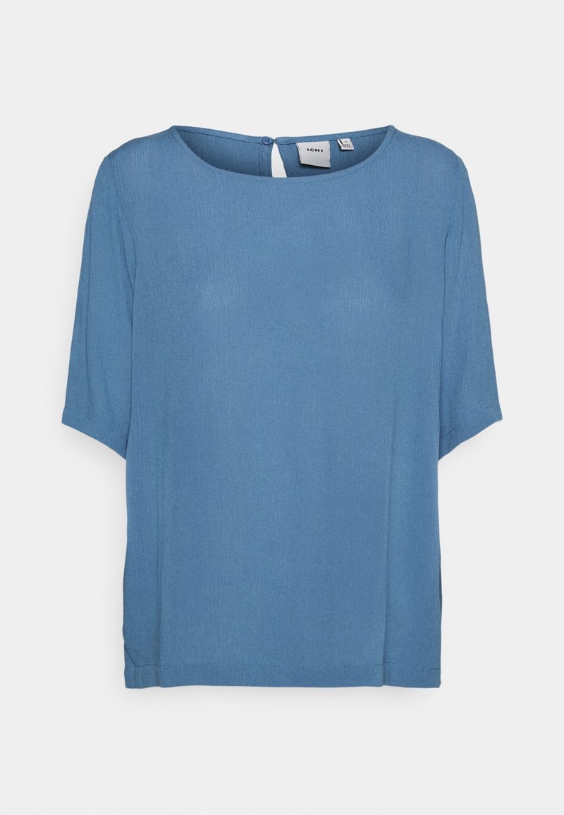 Haut bleu à manches courtes en tissu léger, avec un col rond, une fermeture à boutons à l'arrière et des fentes latérales pour plus de confort.