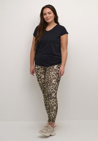 T-shirt en V navy associé à des leggings en imprimé léopard moulants beiges et marron, dotés d'une texture lisse et d'une taille élastique.