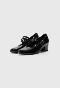 Escarpins Mary Jane en cuir noir avec un bout pointu, dotés de deux fines brides et d'un petit talon bloc, texture lisse et finition brillante.
