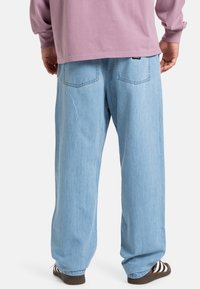 Lys blå denim bukser med løs passform, med to baklommer og rett ben-design. Kombinert med en lavendel langermet skjorte.
