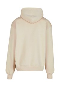 Beige hættebluse med hætte, kengurulomme, ribbede cuffs og kant, samt en blød tekstur. Designet har en afslappet pasform og nedadgående skuldre.