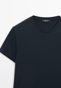 T-shirt in cotone blu navy con finitura testurizzata, dotato di maniche corte e cuciture arancioni a contrasto sulla cucitura della spalla.
