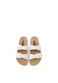 Sandali bianchi a slip-on con due cinturini regolabili a fibbia, una morbida soletta marrone e design aperto sulla punta. Materiale liscio e suola piatta.