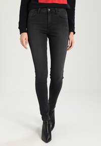 Jeans ajustados de un gris oscuro, hechos de denim con una textura suave, que cuentan con un diseño clásico de cinco bolsillos y un cierre de botón en la cintura.