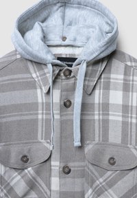 Szara koszula-kurtka w kratę z jasnoszarym kapturem. Posiada podwójne kieszenie na piersi, brązowe guziki oraz miękką fakturę materiału.
