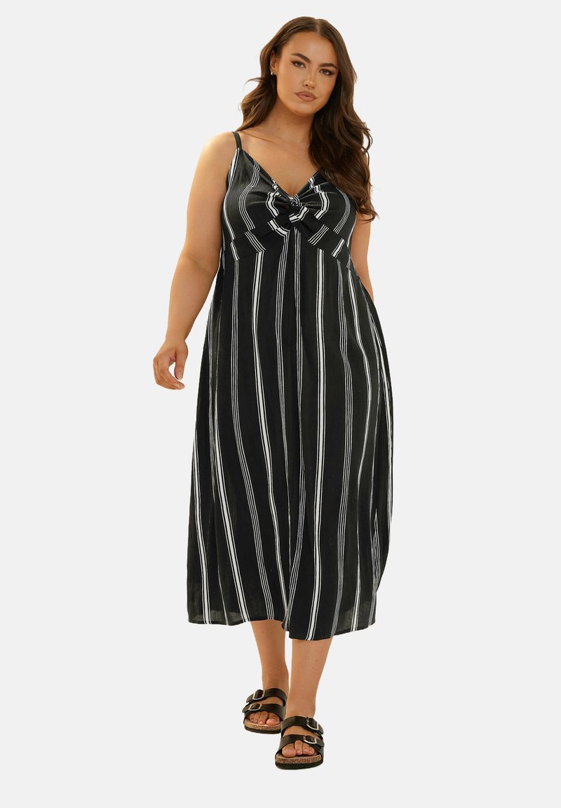 Svart och vit randig midiklänning med en knutdetalj fram, justerbara axelband och en svängig silhuett.