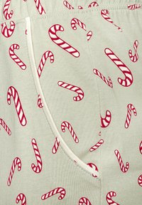 Nahaufnahme eines Stoffes mit rotem und weißem Zuckerstangenmuster sowie sichtbarer Seitennaht und Taschenumriss.