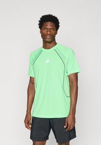 Light green athletic shirt with short sleeves, contrast black accents along the seams, and a small white logo on the chest.