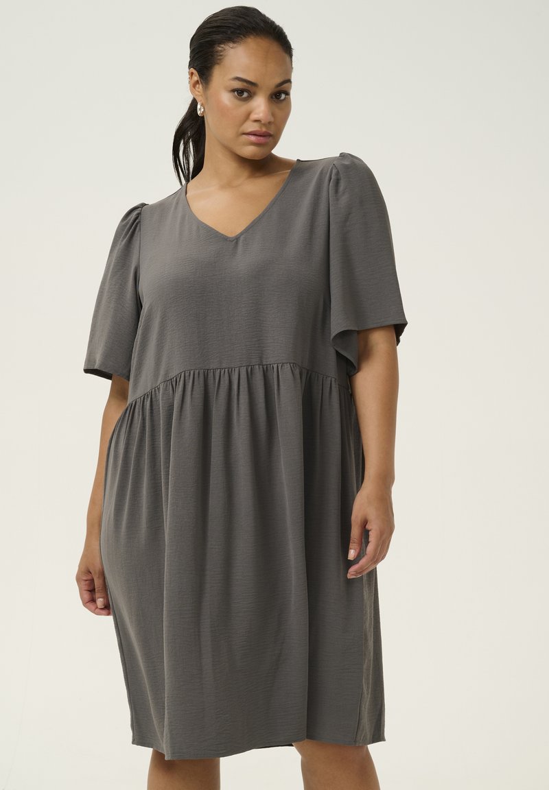 Vestido gris con mangas cortas abullonadas, escote en V y cintura fruncida. Hecho de una tela texturizada, cae justo por encima de las rodillas.
