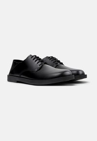 Schwarze Leder-Schnürschuhe mit glatter Oberfläche, runder Schuhspitze und flacher Gummisohle. Einfaches Design mit minimalen Nähdetails.