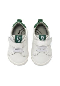 Chaussures en cuir blanc avec des accents verts, dotées d'une bande Velcro, de lacets et d'une semelle intérieure texturée. Bout arrondi et talon rembourré.