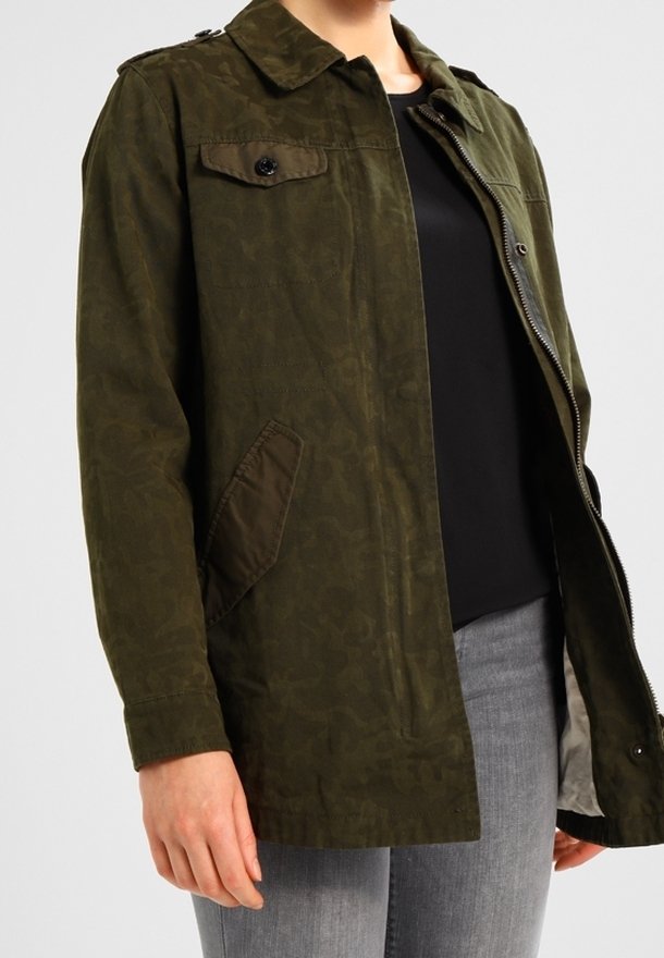Giacca verde oliva con un motivo sottile, dotata di colletto, tasche anteriori e chiusura con zip. Realizzata in tessuto leggero.