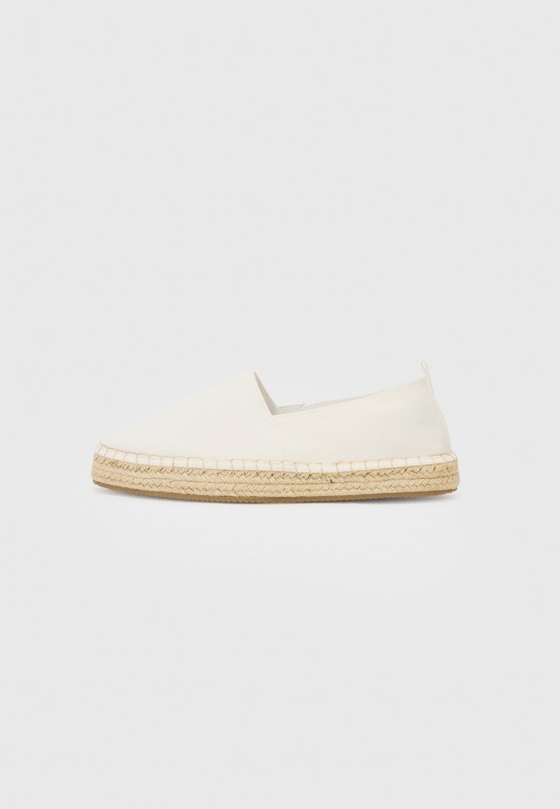 Espadrille blanche à enfiler avec semelle en jute tressé et design minimaliste sur fond neutre.