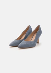 Scarpe con tacco alto in suede blu, con punta affusolata, silhouette slanciata e design con apertura bassa nella parte anteriore. Suola in gomma e lievi accenti metallici.