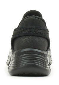 Scarpa sportiva nera con una parte superiore sintetica texture, un colletto imbottito e una suola in gomma segmentata per flessibilità e aderenza.
