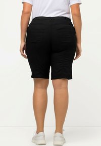 Zwarte casual shorts met een aansluitend ontwerp, voorzien van twee achterzakken en een gladde textuur. Draag ze met een wit t-shirt en sneakers.