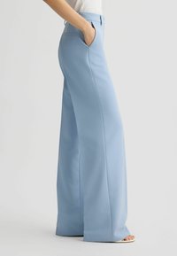 Helle blaue, weit geschnittene Hosen aus glattem Stoff. Mit seitlichen Taschen und einer taillierten Passform, die eine klare, elegante Silhouette bietet.