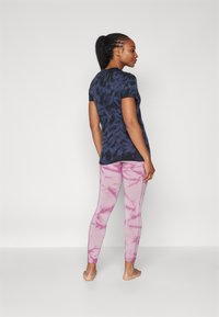 Námornícky tričko s krátkym rukávom s tie-dye vzorom je skombinované s svetloružovými legínami s mramorovým vzorom. Obe oblečenia sú priliehavé a pohodlné.