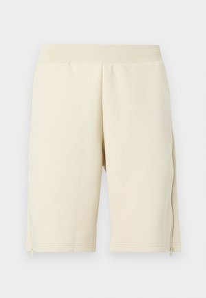 Pantaloni corti color crema realizzati in tessuto morbido, con una trama liscia, una vita elastica e tasche laterali con zip.