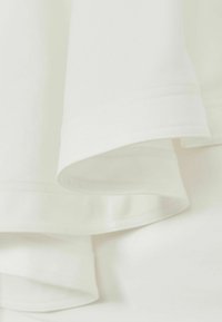 Vitt tyg med slät textur, med vikta kanter och subtila sömnadsdetaljer. Materialet verkar lätt och mjukt.