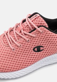 Roze mesh sneaker met zwarte accenten, ronde veters, een getextureerde zool en een opvallend logo aan de zijkant. Lichtgewicht ontwerp voor ademend vermogen.