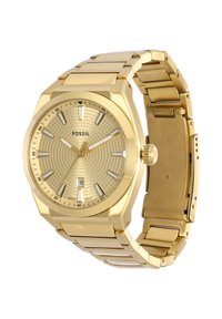 Reloj de pulsera Fossil en tono dorado con esfera estampada, marcadores de hora plateados, ventana de fecha a las 6 en punto y cierre de pulsera metálico enlazado abierto.
