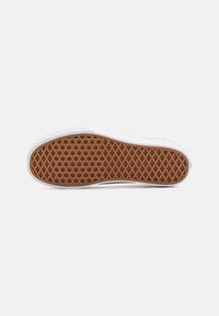 Rubber sneaker sole in white and brown, featuring a hexagonal pattern for grip. Smooth edges with a textured surface for traction.