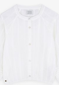 Blouse blanche à manches longues avec un col rond, motif texturé et légère brillance. Comprend cinq boutons et des poignets froncés. Étiquette de marque visible.